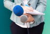 a reporter holding two microphones and a pencil and notepad